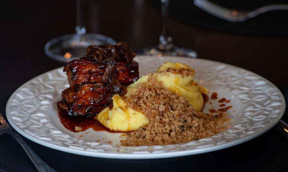 curry pasta Pancetta glaceada com melado de cana e especiarias, purê de batata salsa, cebola caramelizada, glace e farofa de castanha (Divulgação). ceia natal réveillon curitiba