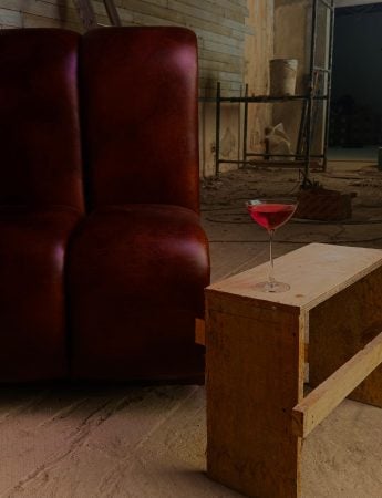 ambiente de obras, com uma poltrona vermelha e uma taça de vinho