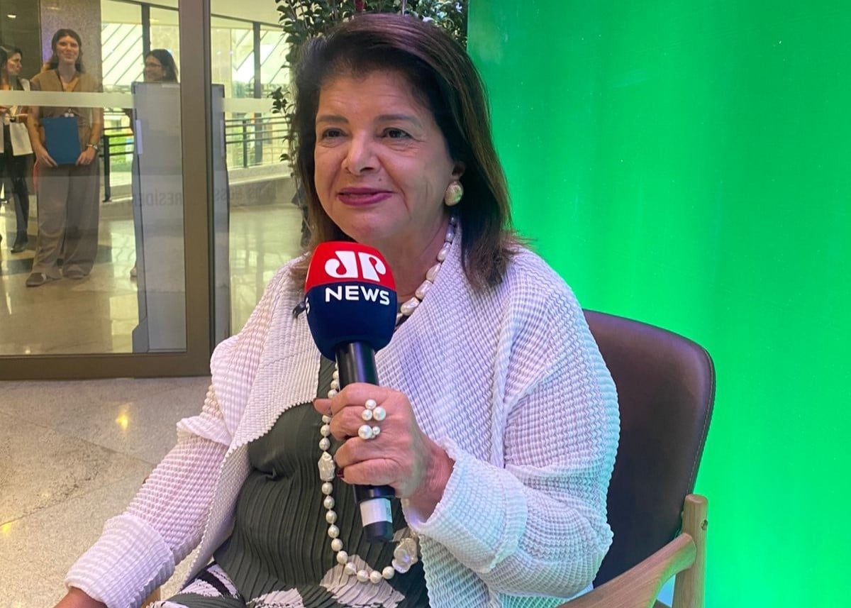 Luiza Trajano sentada em uma cadeira segurando um microfone