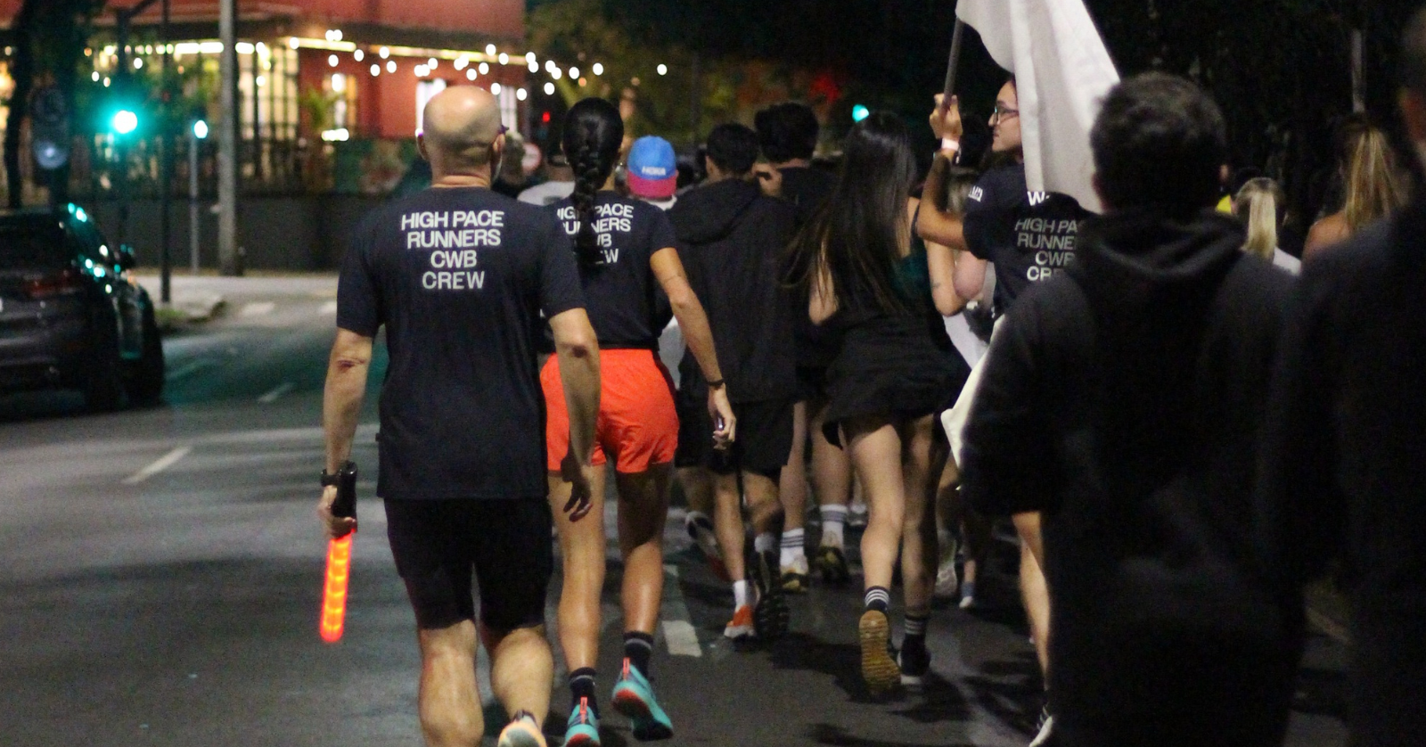 Grupo de pessoas de costas correndo na rua de noite