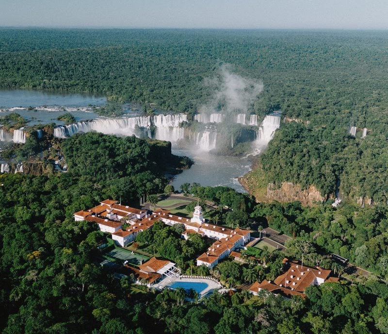 floresta com as quedas dágua de foz do iguaçu ao fundo e o hotel cataratas ao meio