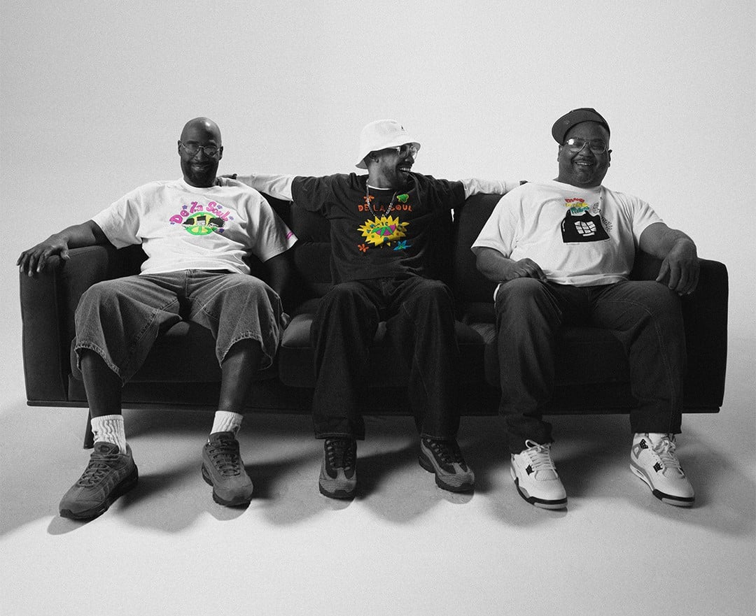 tr~es homens sentados em um sofá vestindo as roupas da nova coleção